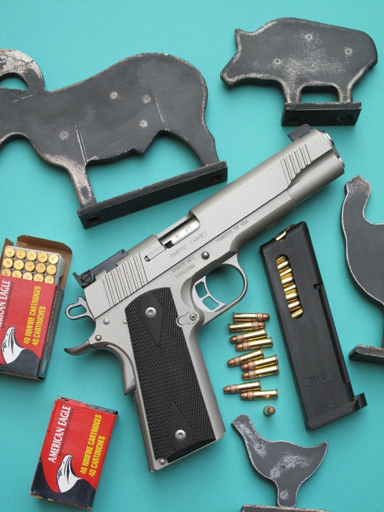 Le Kimber Rimfire Target « Silver », qui reprend avec une grande exactitude l’aspect et les dimensions du Colt 1911 A1, se démarque par sa finition chromée satinée et par ses plaquettes en néoprène. Pour les besoins de la photo, il est accompagné ici des mini-silhouettes métalliques destinées aux armes d’épaule de calibre 22 Long Rifle, plus petites celles dédiées aux armes de poing de même calibre.