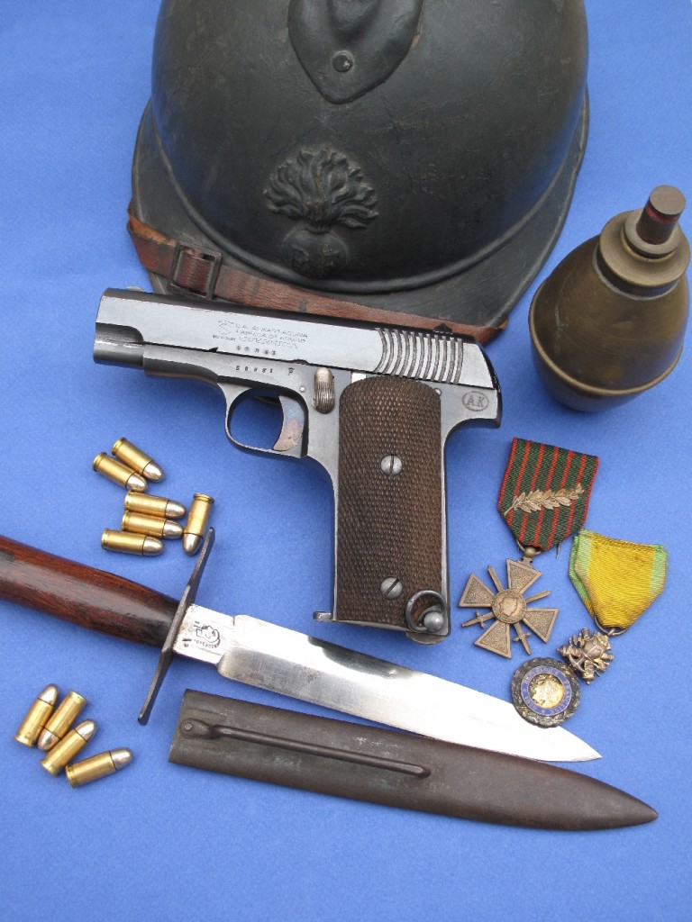 Le pistolet Alkar type Ruby 14-18 dans son environnement historique de la « Grande Guerre » : casque Adrian modèle 1915, grenade « citron » suffocante (éther bromacétique) avec allumeur à friction, poignard de tranchée modèle 1916, fabriqué à Thiers par la maison Bourgade aîné (poinçon « tête de chinois »), croix de guerre et médaille militaire.