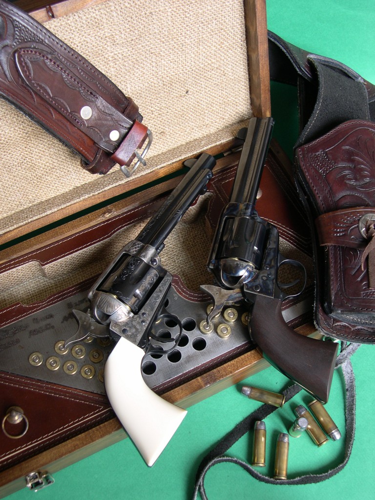 Les répliques du Colt Single Action Army 1873 « Peacemaker » produites par les firmes italiennes Pietta et Uberti sont posées sur un coffret « Old West » fabriqué par Pietta, originale reproduction d‘un modèle ancien en pin, garni de toile et de cuir, et accompagnées d’un holster en cuir ciselé de fabrication mexicaine.