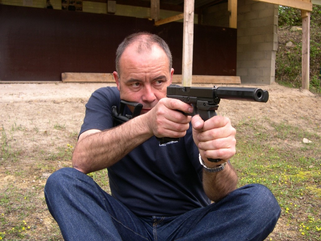 Appréciable en position assise, la poignée d’appoint (constituée par un chargeur de secours muni du talon GMFG) sera délaissée en position debout, l’appui du coude le long du corps procurant une meilleure stabilité pour le tir de précision.